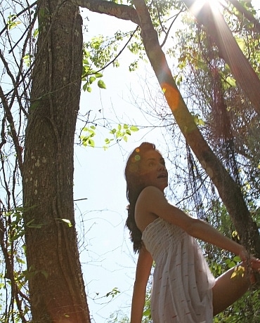 Layla outside nude climbing a tree