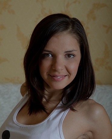 Madlen in a tank top and jeans on her bed